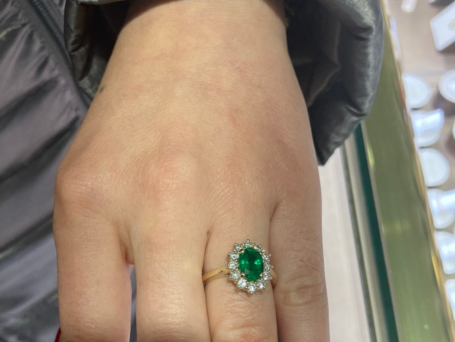 Customer photo: oval emerald and diamond halo engagement ring worn on hand, from Lee's Google review