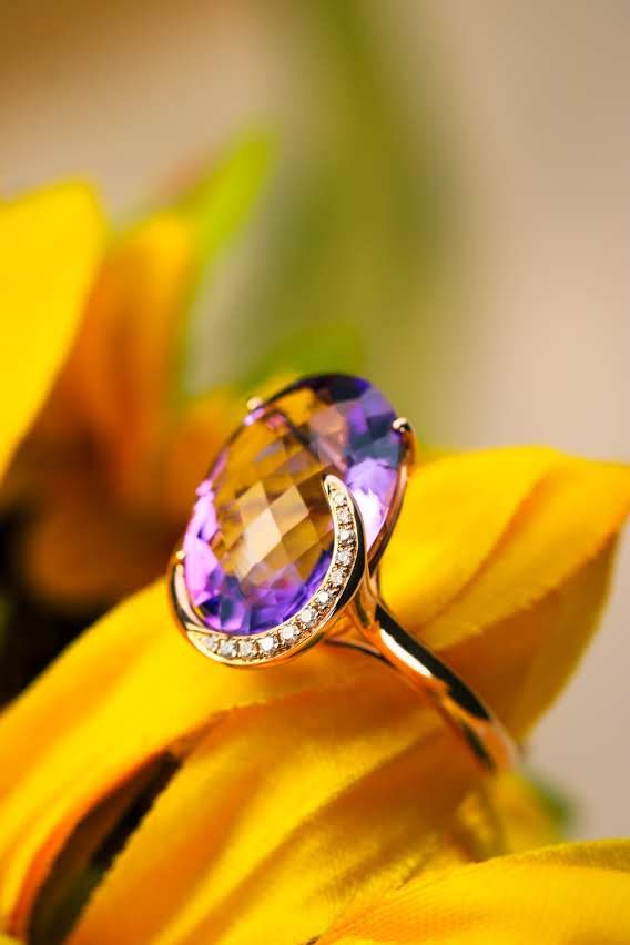 Oval amethyst cocktail ring with natural diamond crescent in gold, resting on sunflower petals