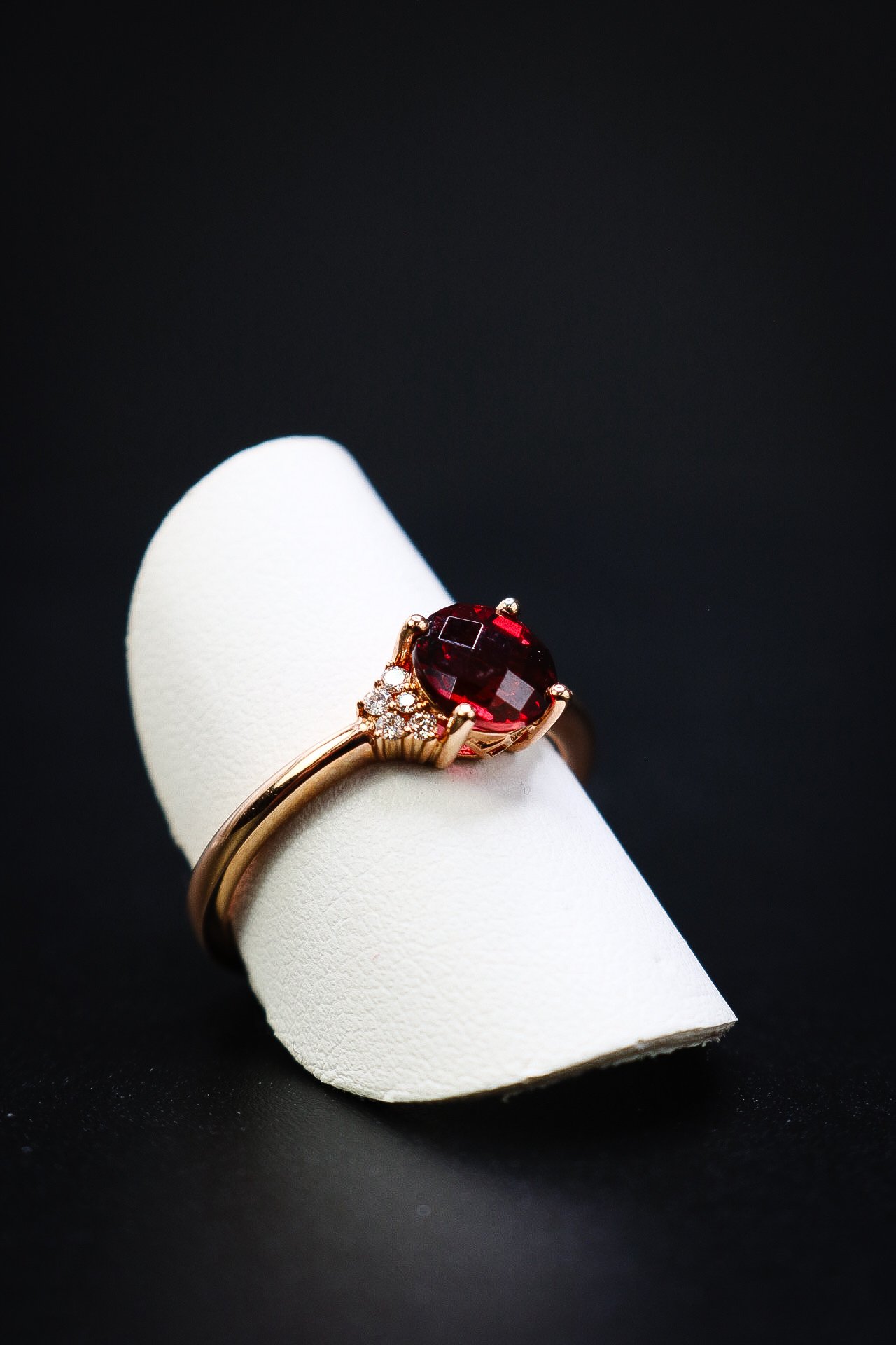 Checkerboard-cut garnet ring with side diamonds on a rose gold band