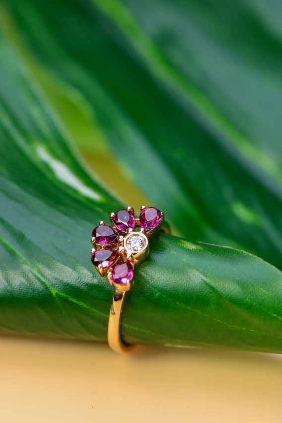 Gold ring with a blossom of pear-cut pink sapphires around a central natural diamond, on a leaf