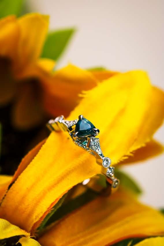 Alexandrite trillion ring in white gold with milgrain details and natural diamonds, on sunflower petals